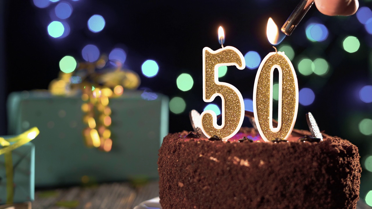 桌上甜蛋糕上的50岁生日蜡烛，50岁生日。8、火从打火机里冒出来，吹灭了节日的蜡烛。视频素材