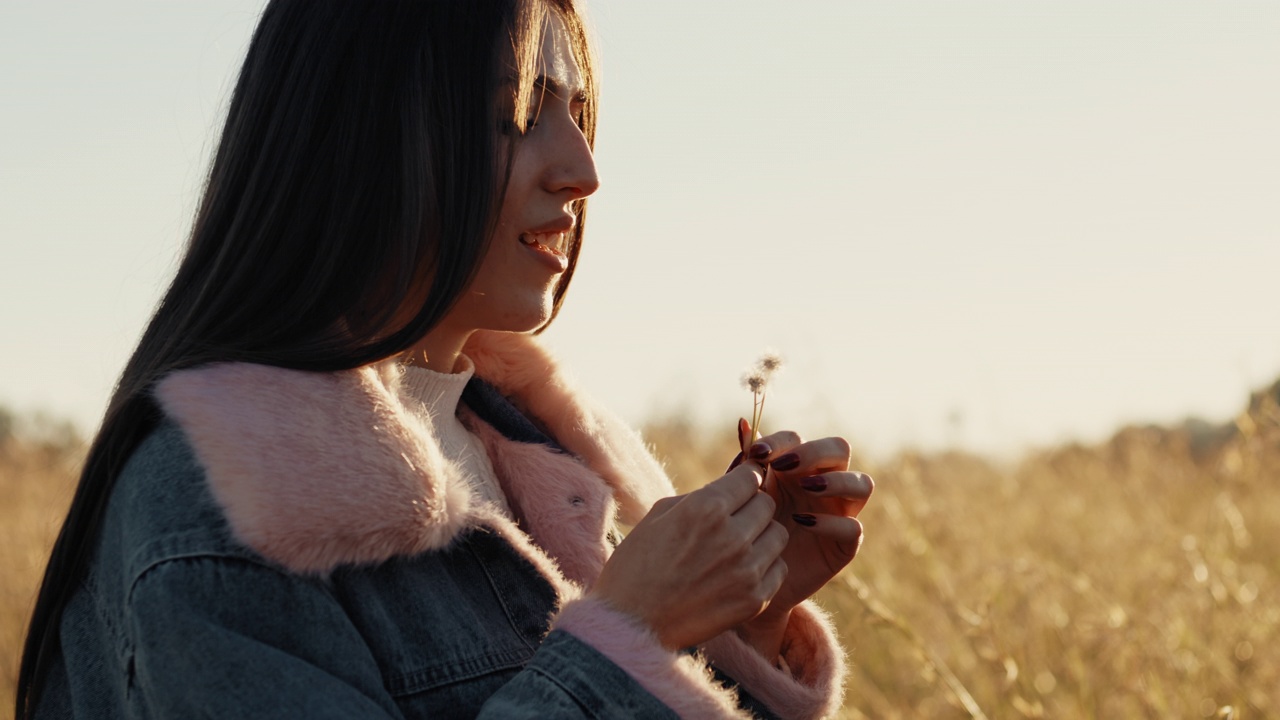 日落时吹蒲公英的女孩的特写视频素材