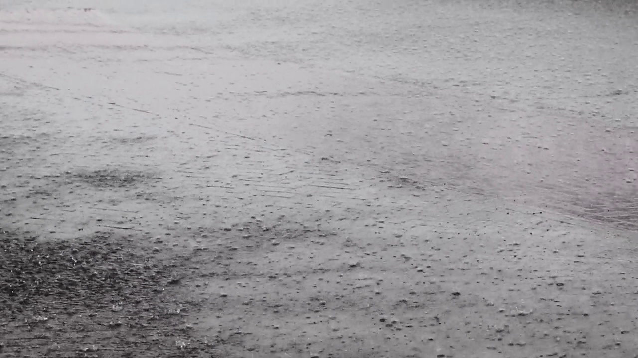 在一场大雷雨中，大雨滴落在城市沥青上。视频素材