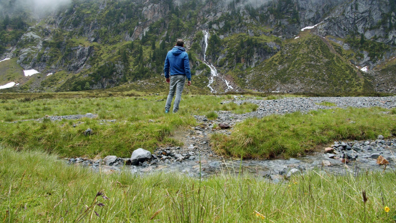 徒步旅行者沿着徒步路线走向高山峡谷中的瀑布山。户外积极的生活方式理念视频素材