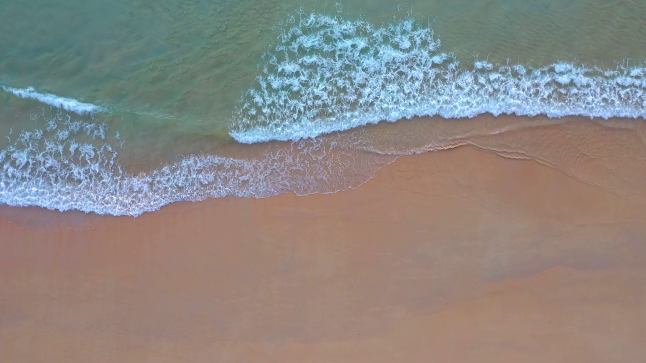 空中俯瞰绿色的海浪拍打在沙滩上。视频素材