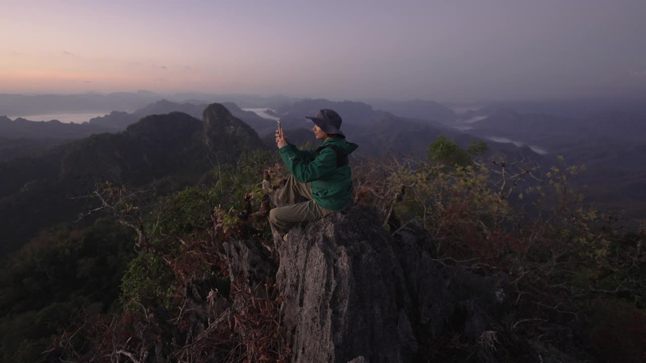 女徒步旅行者用智能手机在山上拍照视频素材