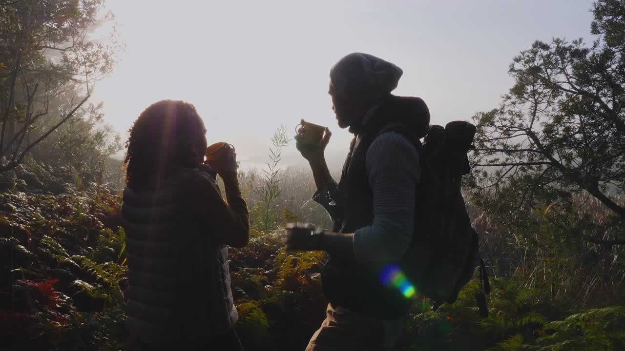 剪影徒步旅行者夫妇喝咖啡在阳光明媚的早晨秋天的树林视频素材