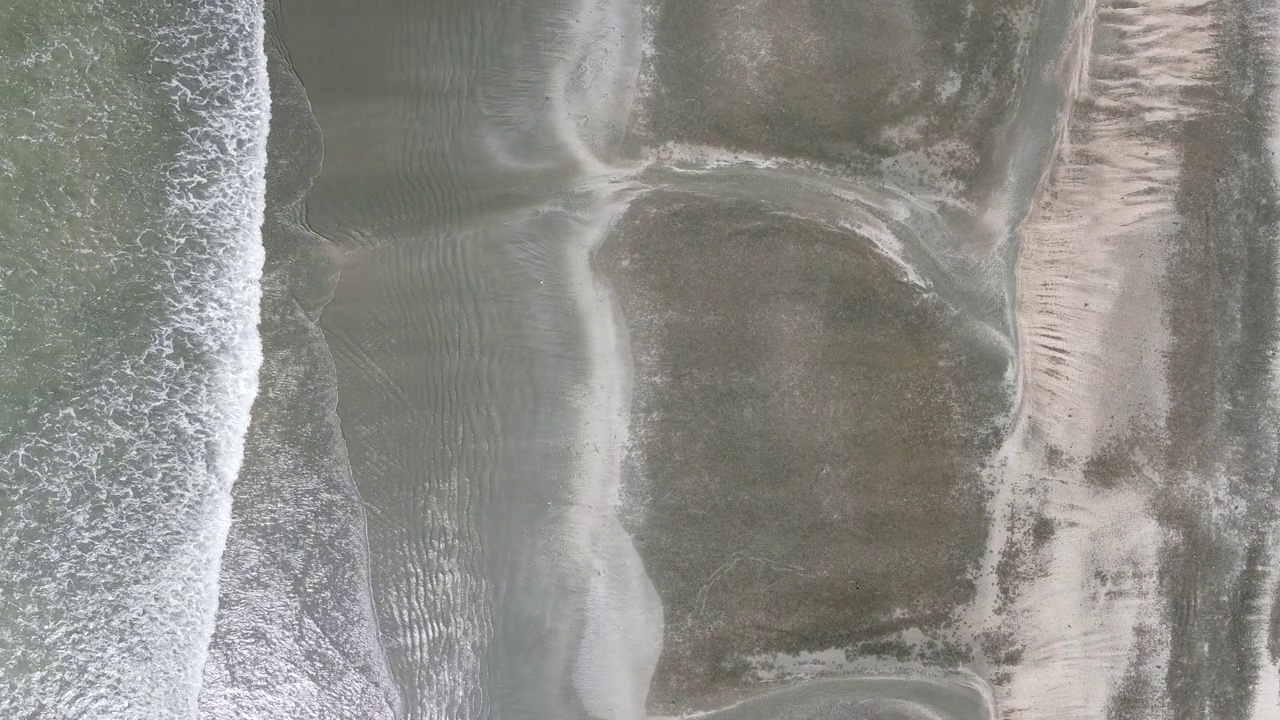 4K运动的软波和蓝色的海洋在沙黑色的海滩背景视频素材