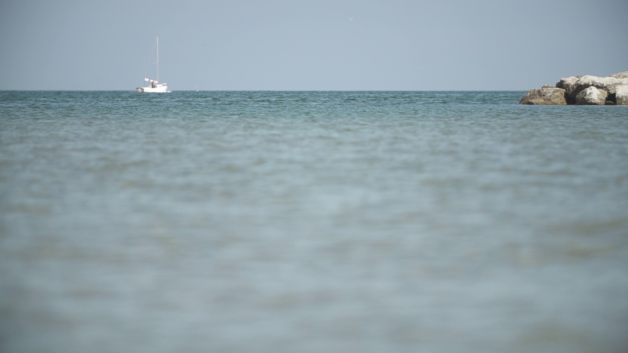 波浪在海面上缓慢移动，有岩石和船只视频素材