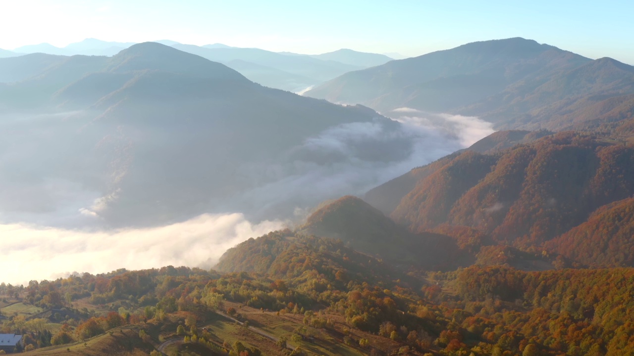 在一个阳光明媚的日子里，一架无人机飞过风景如画的秋山。视频素材