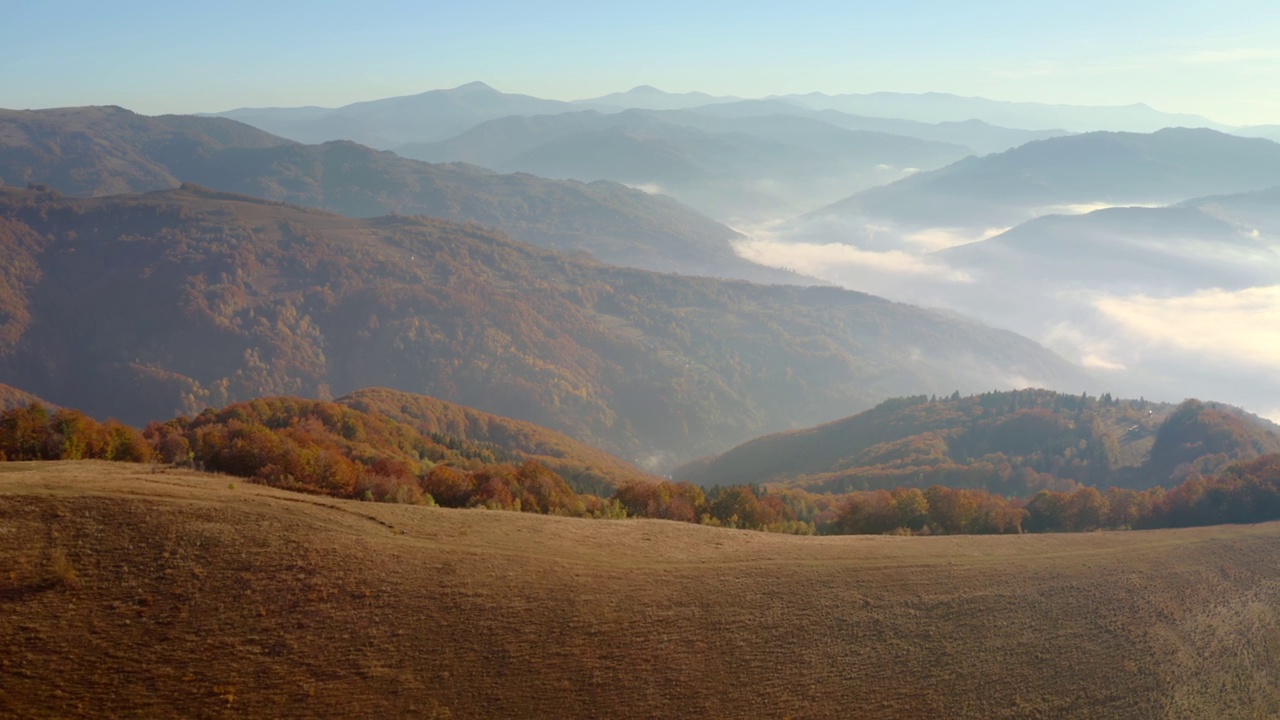 在一个阳光明媚的日子里，一架无人机飞过风景如画的秋山。视频素材