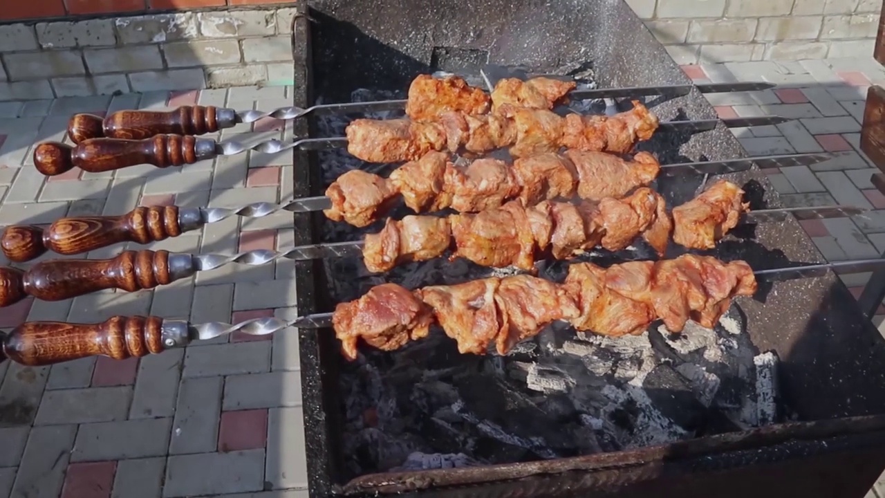 一个男人在烤肉。在燃烧的煤块上串上烤肉。美味的烧烤食品。在烤架上煎肉，带皮。视频素材