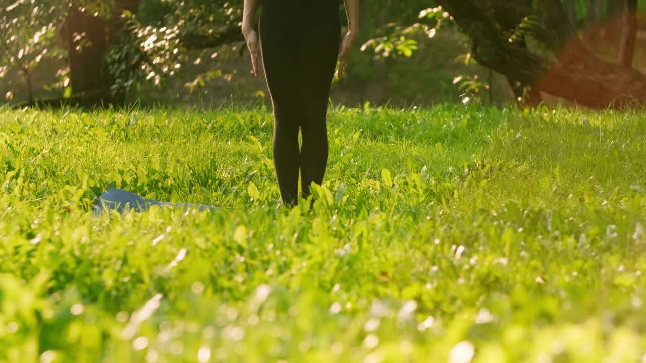 柔韧的女人在户外练习瑜伽。年轻女子在绿草地上训练。视频素材