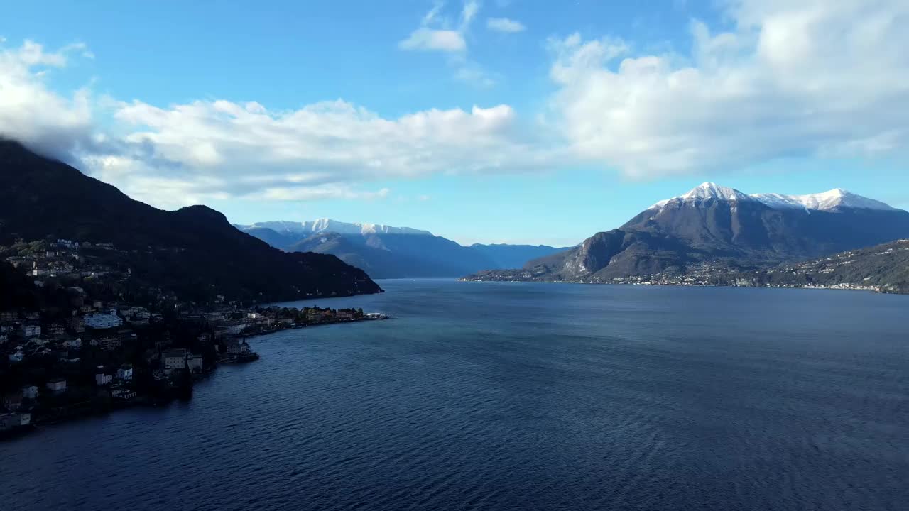 无人机观看科莫湖与城镇两侧，天空，云和雪覆盖阿尔卑斯山的山峰。视频素材