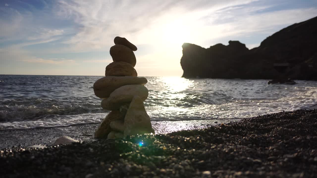 金字塔的石头在一个阳光明媚的日子在蓝色的海洋背景上。节日快乐。卵石滩，风平浪静的大海，旅游胜地。快乐假期的概念在海上,冥想,水疗,冷静视频素材