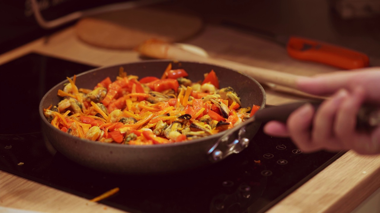 女厨师用木勺在煎锅中搅拌食材。视频素材