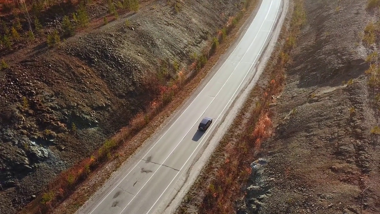 鸟瞰图的汽车驾驶在阳光明媚的秋天乡村公路公路。电影无人机拍摄飞越车辆行驶在碎石路上，秋天的风景。当地旅游，自驾游，度假。视频素材