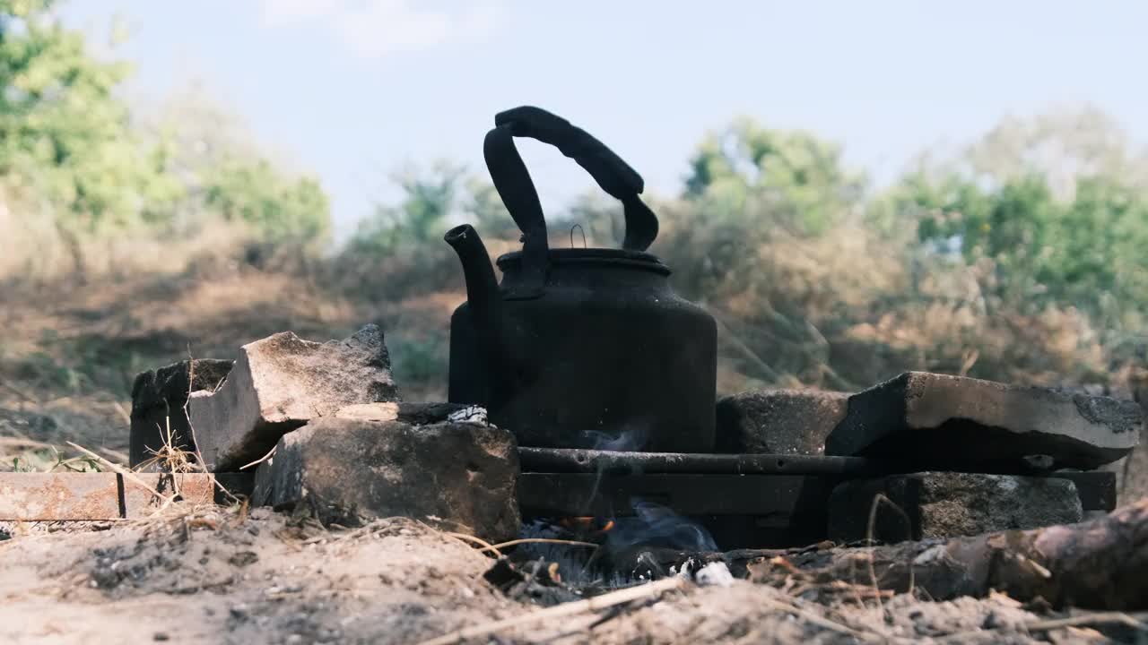 旅游水壶站在一个自制的篝火炉在旅游营地的自然视频素材