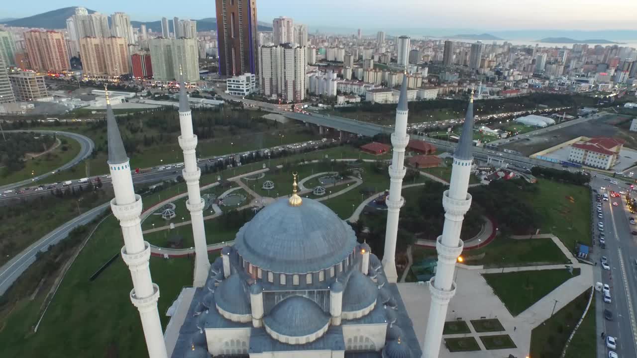 4k无人机电影观看照明夜景巨大的伊斯兰清真寺与拥挤的城市视图-现代和传统的伊斯兰建筑寺庙之间的摩天大楼和高速公路无人机拍摄包括近距离尖塔和圆顶-适合斋月和eid视频素材