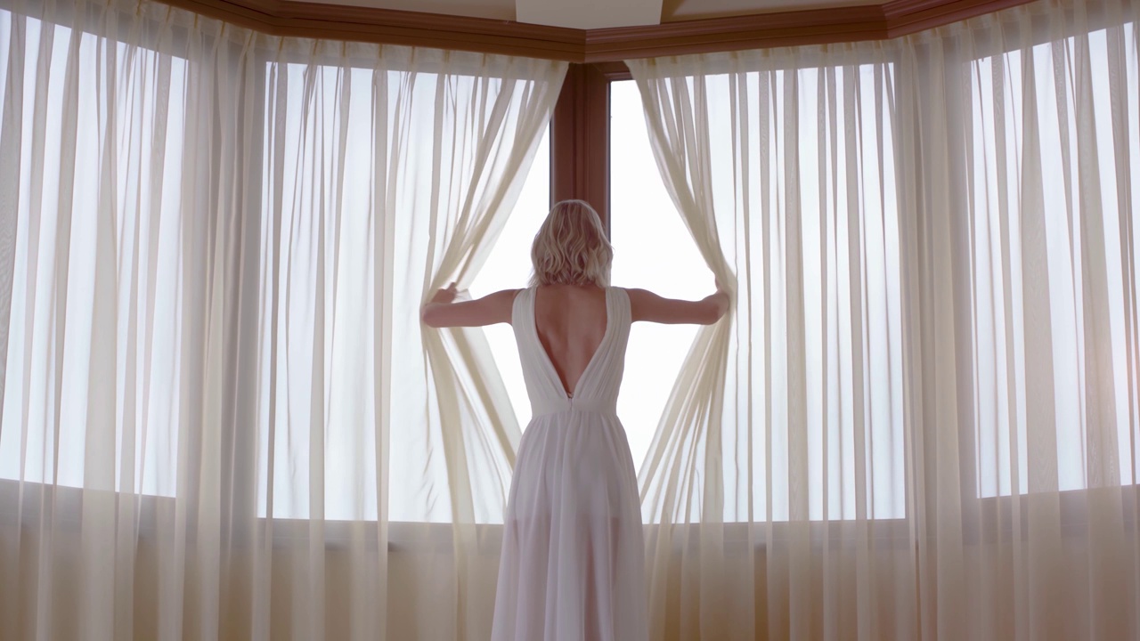 穿白裙子的女人正在拉开窗帘视频素材