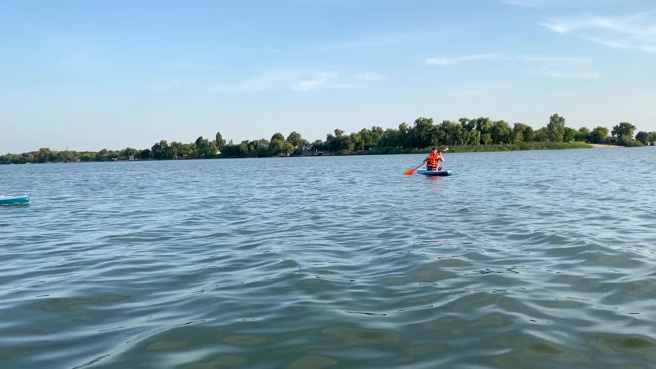 成年快乐的女人和男人在划艇板上游泳。支持老年人冲浪。夏季娱乐休闲，在海中划船。一个活跃的生活方式。水上运动。视频素材