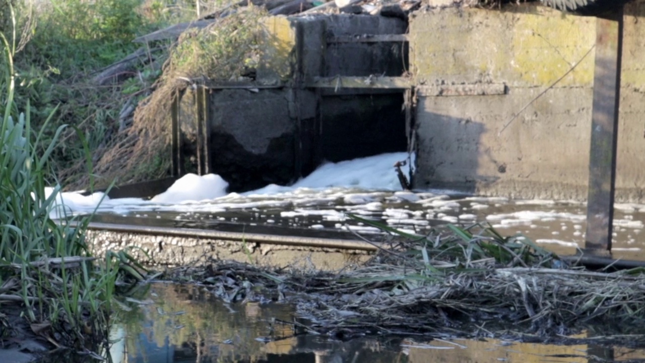 城市的排水沟和污水慢慢地流入河中。污水从城市流入下水道。水污染和工业污水。被污染的水道景色不错。使用的水。视频素材