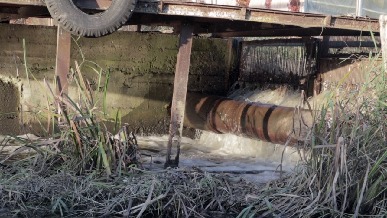 城市的排水沟和污水慢慢地流入河中。污水从城市流入下水道。水污染和工业污水。被污染的水道景色不错。使用的水。视频素材