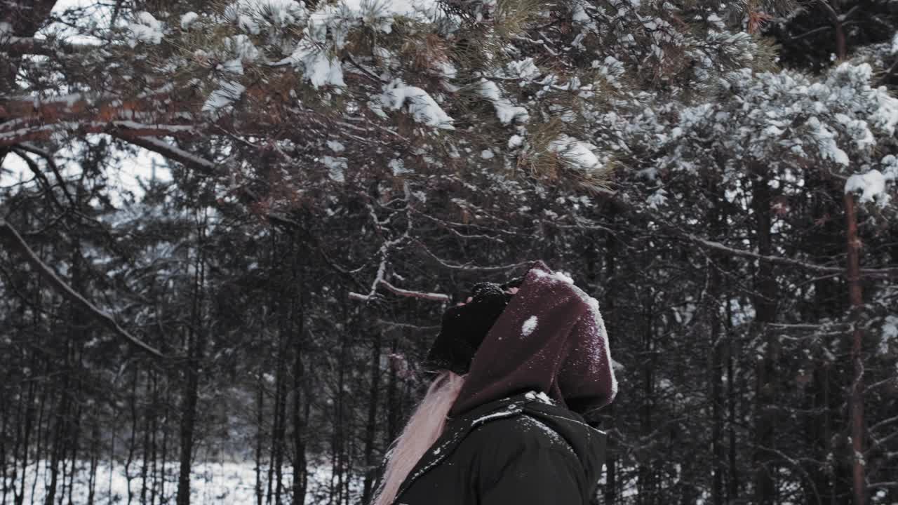 一个戴着巴拉克拉瓦帽的女孩在雪落在她头上的冬天玩得很开心。视频下载