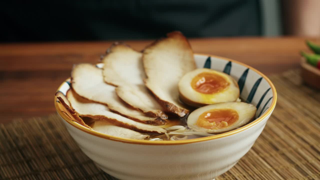 日本拉面亚洲汤面配牛肉或鸡肉，蘑菇和鸡蛋，厨师在传统的韩国中餐烹饪。接近美味的越南美食。视频素材