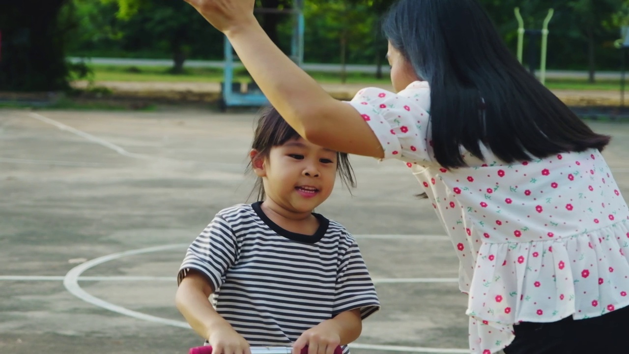 快乐的妈妈和孩子们在夏天的公园里骑着滑板车击掌。在户外玩滑板车的孩子们。儿童休闲活动和户外运动视频素材