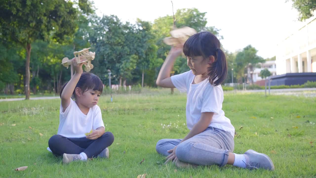 两个亚洲女孩在快乐地玩模型飞机。亚洲同胞们笑了，笑得很开心视频素材