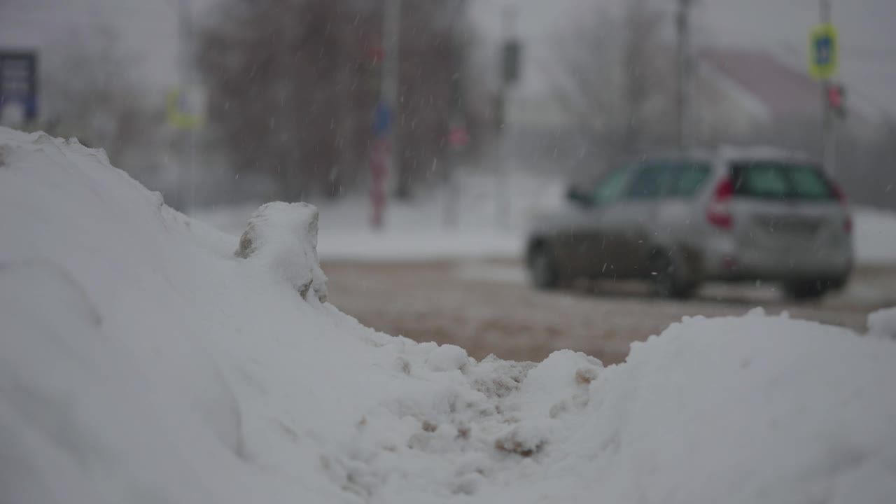 大雪期间的城市道路。汽车在冬天的泥和雪中行驶视频素材