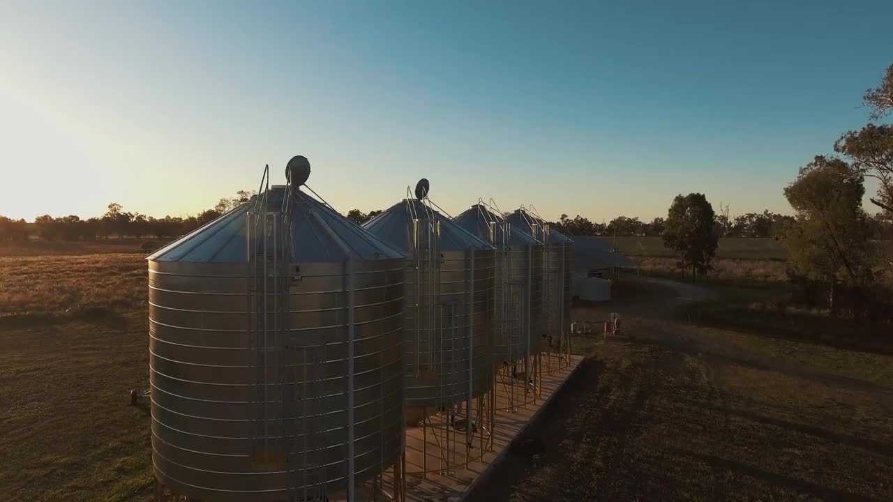 一个美丽的慢动作空中/无人机景观拍摄飞行在风景如画的谷仓在澳大利亚农民内陆财产在日出/日落。拍摄在惊人的4K分辨率视频素材