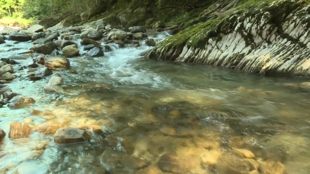 门槛在一个岩石山脉的河流，清澈的水冲破石头视频素材