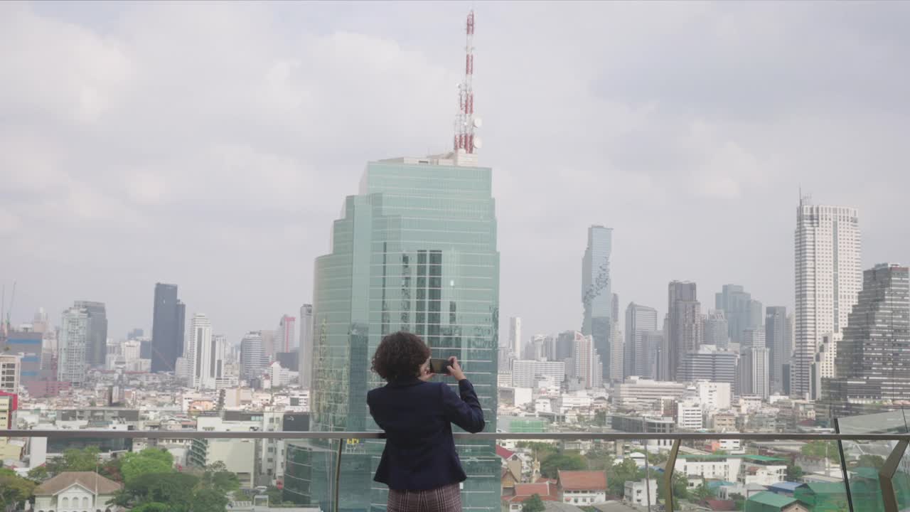 女商人用手机拍摄城市视频，用科技设备的概念来看待人们的生活方式视频素材