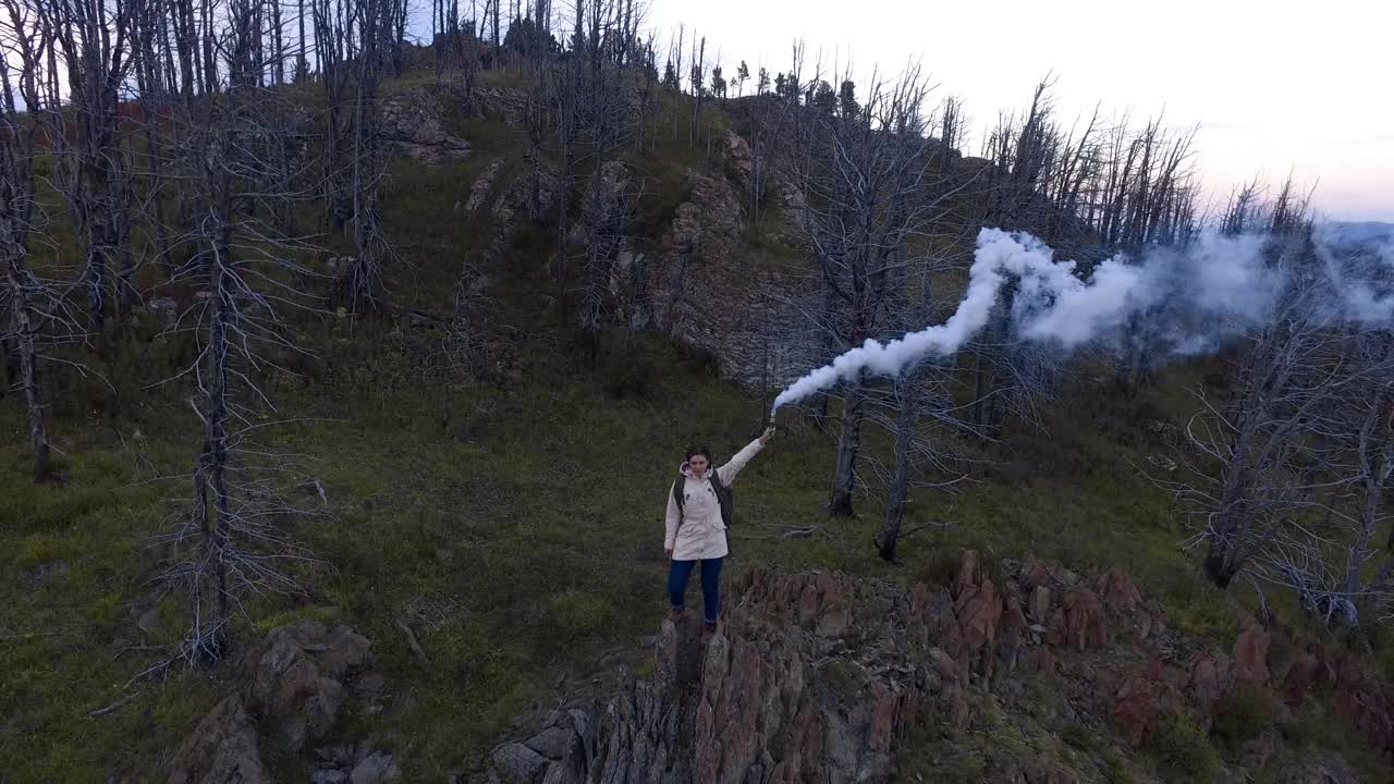 鸟瞰一名女子手持烟雾弹站在悬崖上视频素材