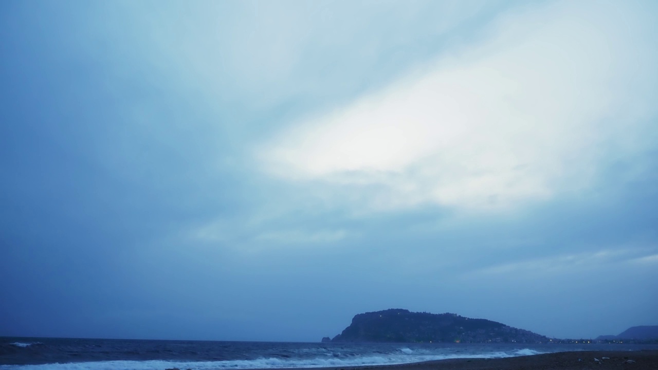 与cloudscape海景。随着时间的推移，海浪撞击着海滩，在黄昏的多云的天空中溅起白色的泡沫。云日落视频素材