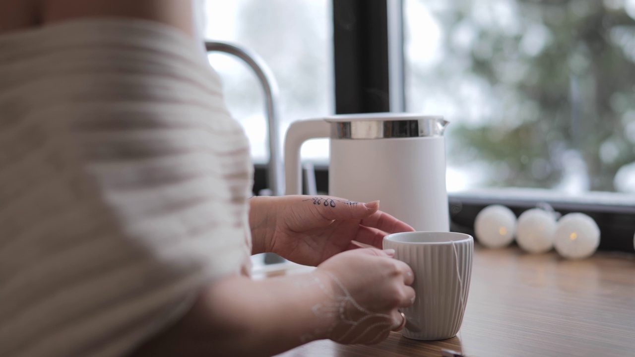 女人手把水壶里的热茶倒进家里的杯子里视频素材