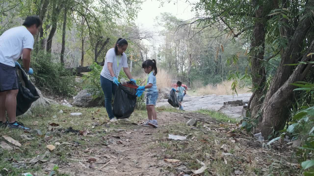 一群亚洲志愿家庭在河边收集垃圾和塑料。把垃圾放在垃圾箱里，帮助保护环境。世界环境日视频素材