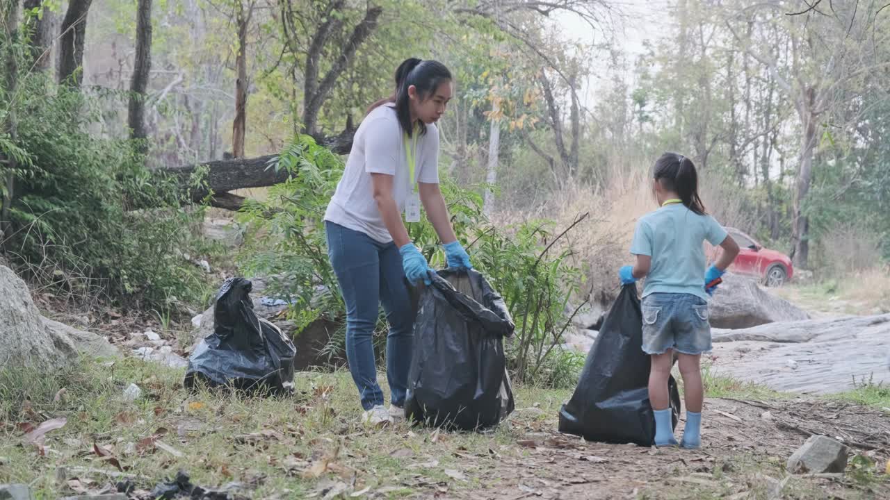 一群亚洲志愿家庭在河边收集垃圾和塑料。把垃圾放在垃圾箱里，帮助保护环境。世界环境日视频素材