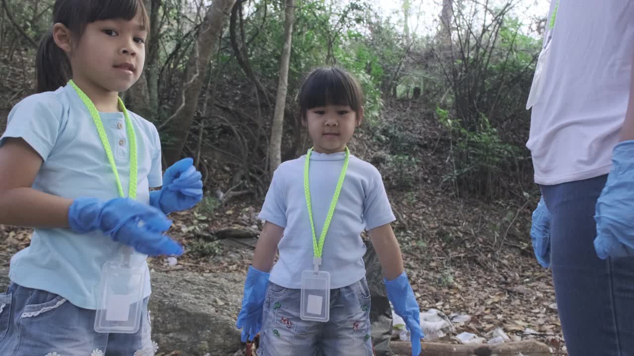 一群亚洲志愿者家庭在河边捡起垃圾。把垃圾放在垃圾箱里，帮助保护环境。世界环境日视频素材