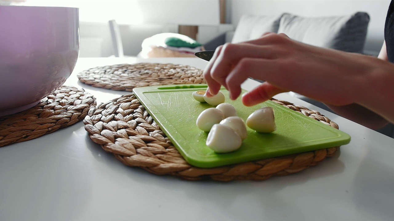 一个年轻的女孩在菜板上切煮鹌鹑蛋视频下载