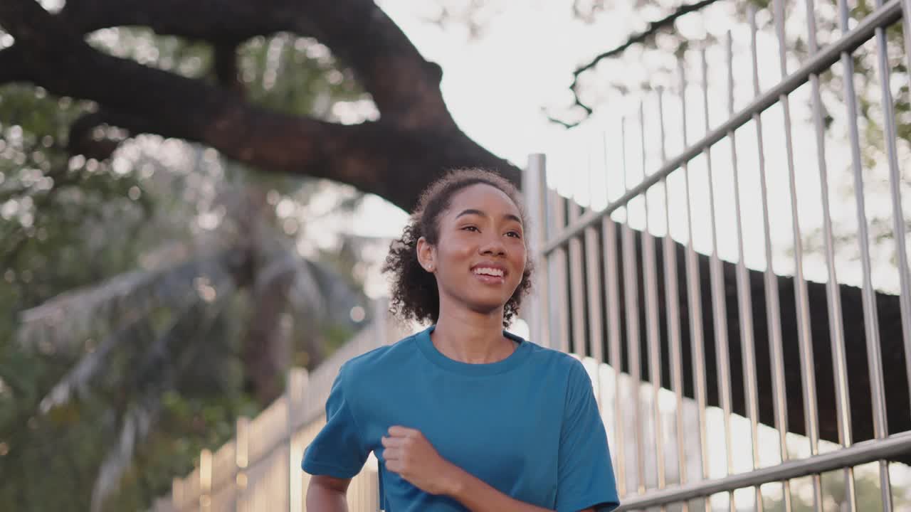 接近活跃的女性，在城市晨曦中跑步健身，开心的微笑。运动妇女在运动服装锻炼慢跑城市街道。运动、健身、健康、积极的生活方式。视频素材