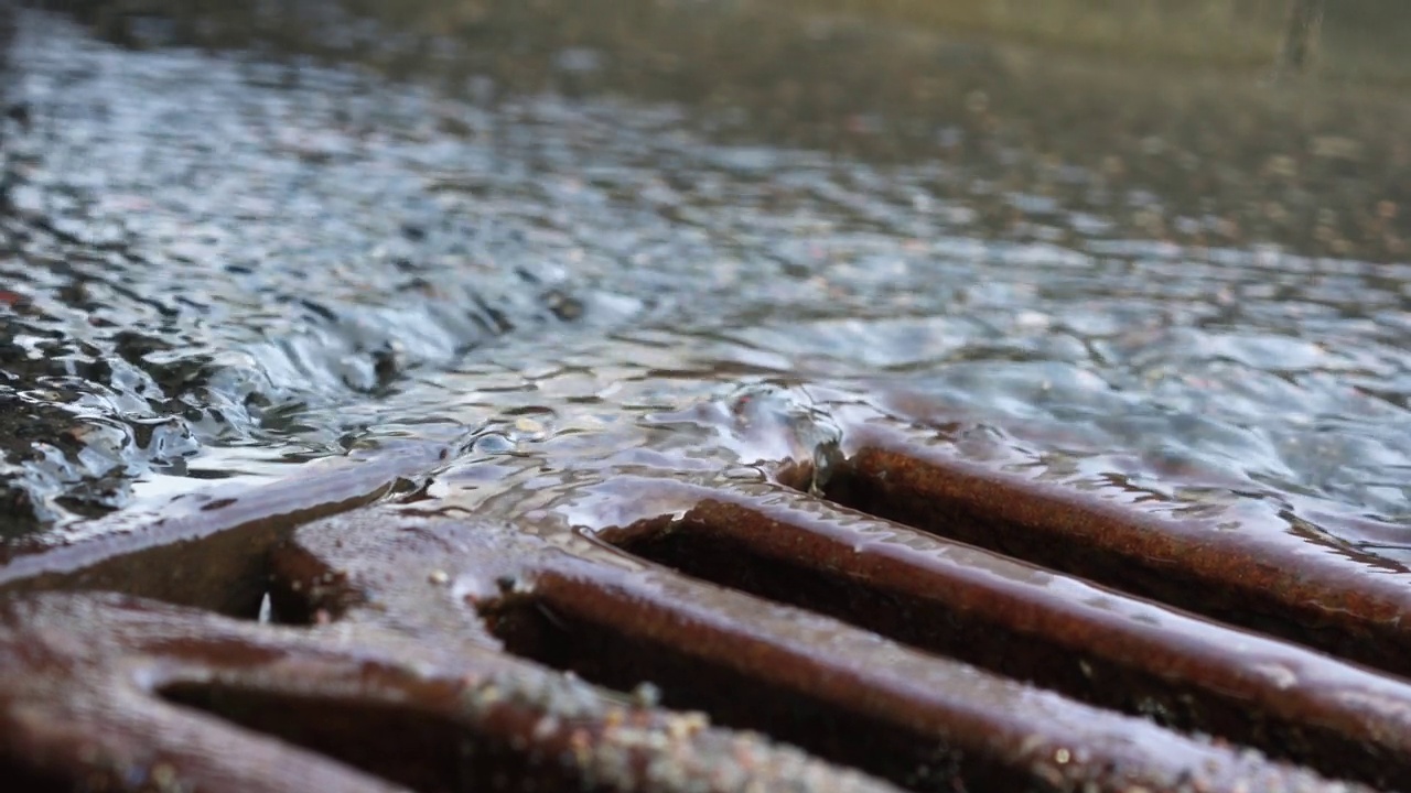 雨水通过沥青路面流入城市街道排水沟视频素材