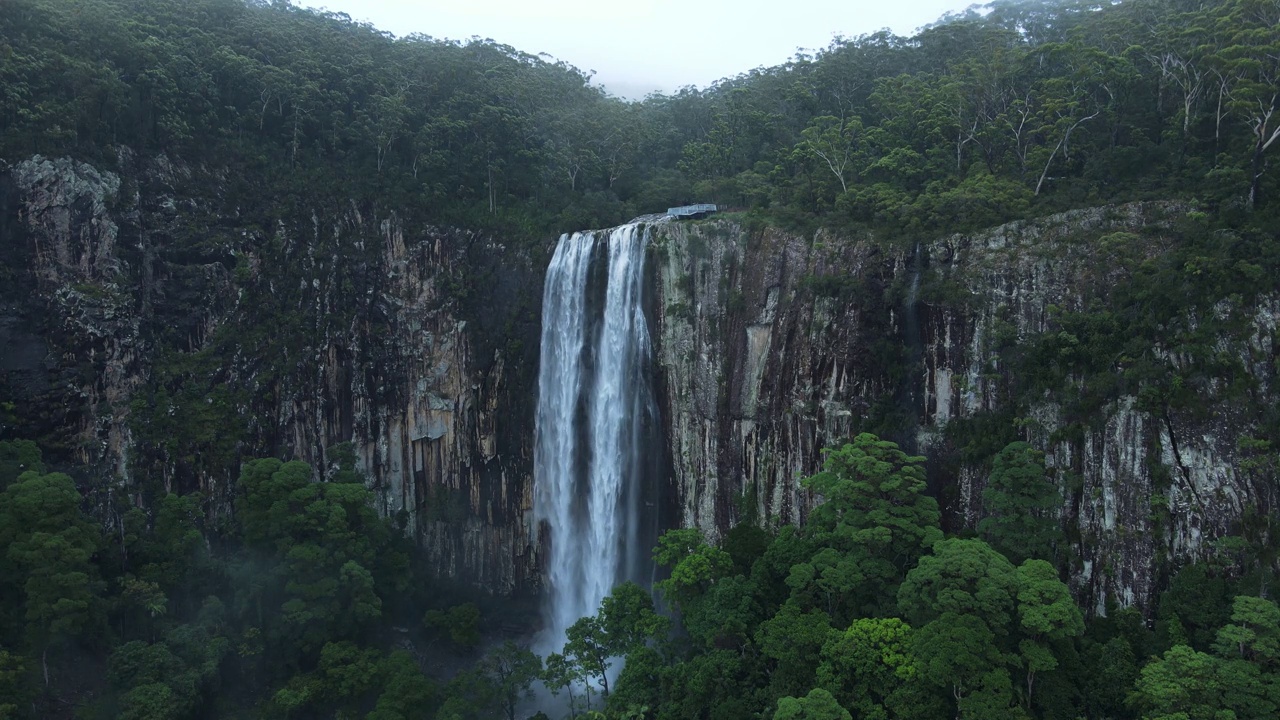 壮观的瀑布从热带雨林覆盖的山上倾泻而下的全景。澳大利亚睡帽国家公园的米永瀑布视频素材