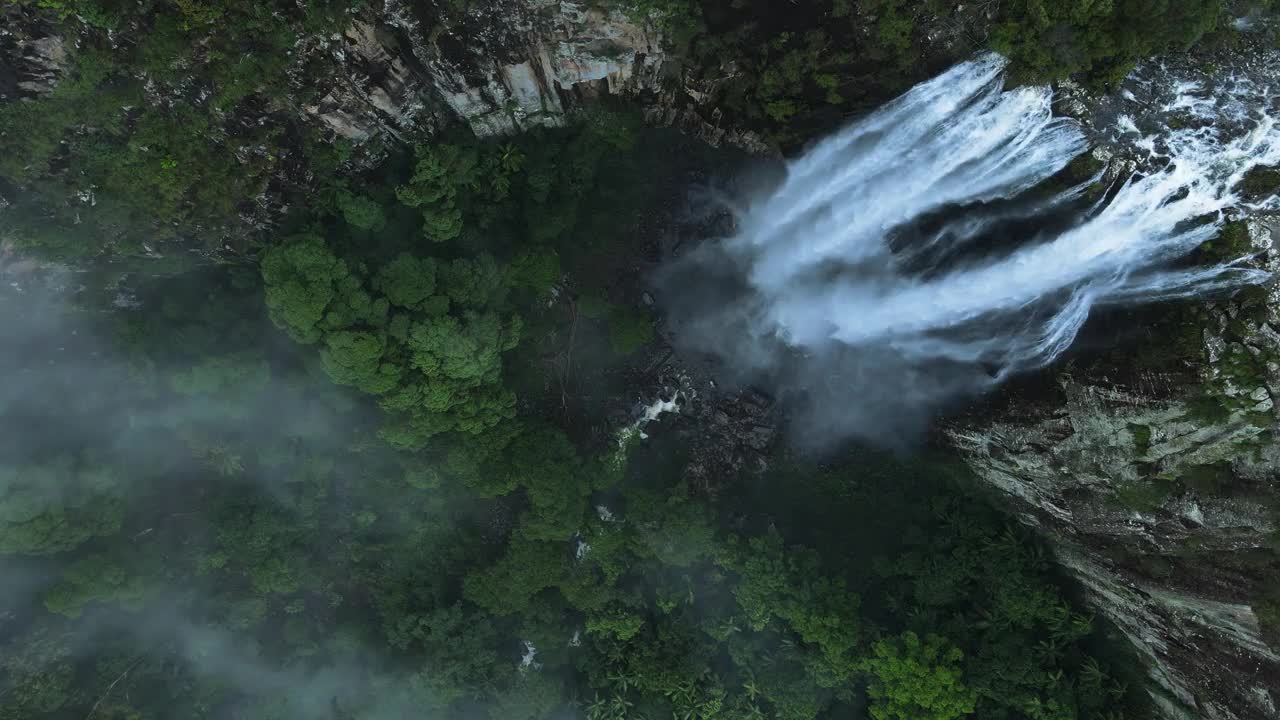 郁郁葱葱的热带瀑布倾泻而下，进入一个被雨林覆盖的大火山口。独特的无人机视图视频素材