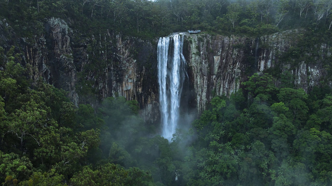 雄伟的瀑布在郁郁葱葱的热带雨林山景中倾泻而下。全景高空俯视图视频素材