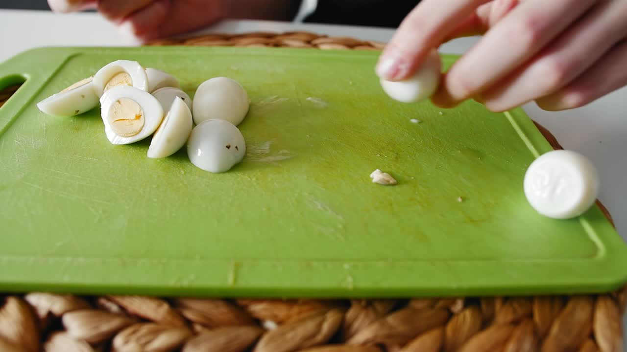 一个年轻的女孩在菜板上切煮鹌鹑蛋视频下载