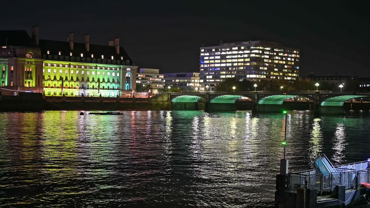 从威斯敏斯特桥到市政厅的平移镜头，以及夜间灯火辉煌的伦敦眼视频下载