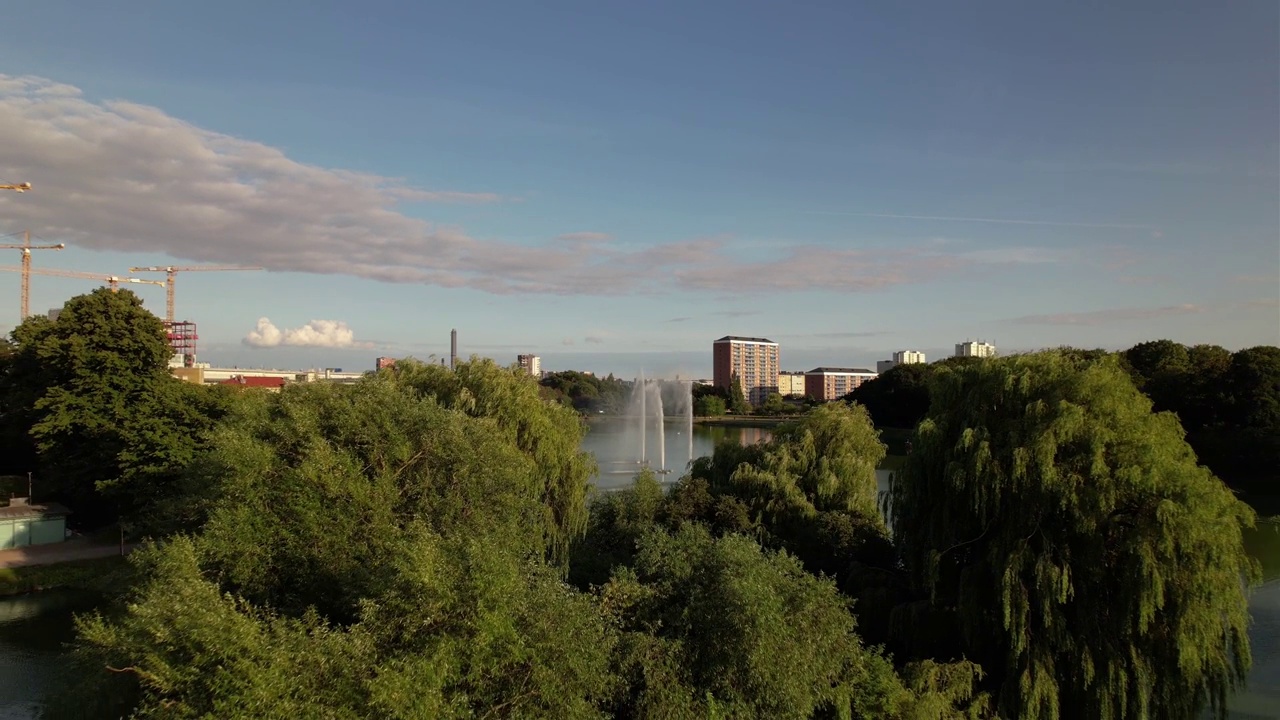 一架向后飞的无人机靠近池塘中的岛屿上的树木，Pildammsparken Malmö，瑞典视频素材