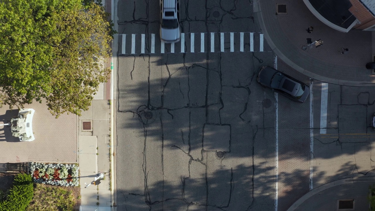 空中的俯仰无人机视图的行人在道路上的交叉。汽车在城市街道上行驶。伊利诺斯州内伯维尔大街上的许多家庭。视频下载