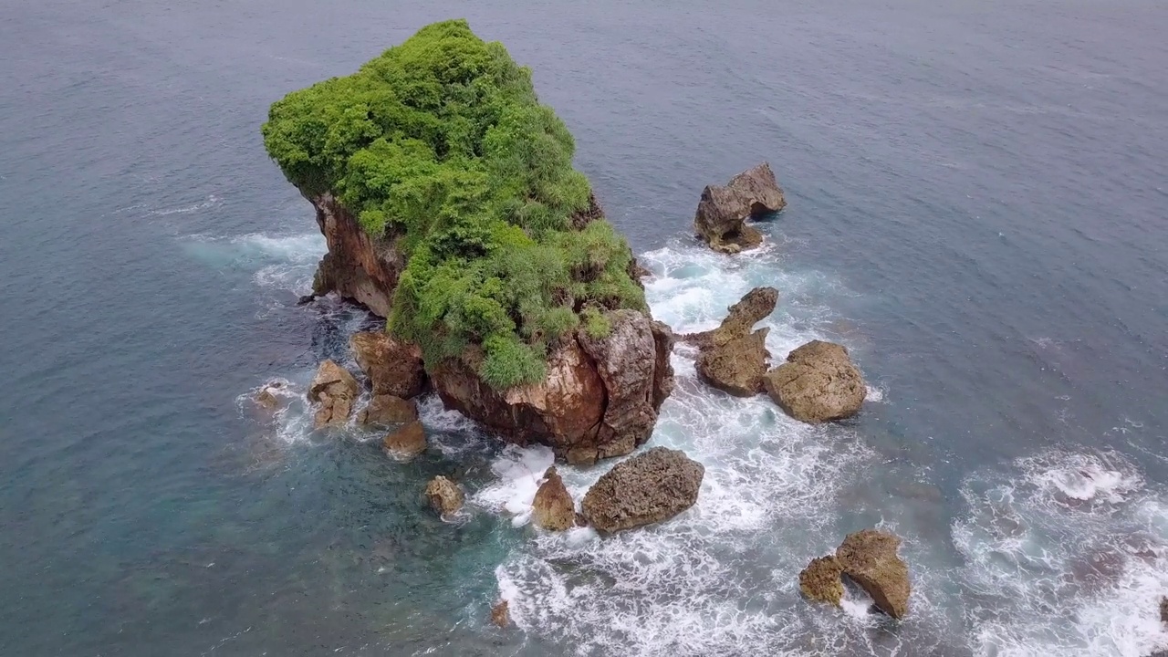 无人机拍摄的珊瑚岛被绿树覆盖，被热带海滩的海浪拍打着。视频素材