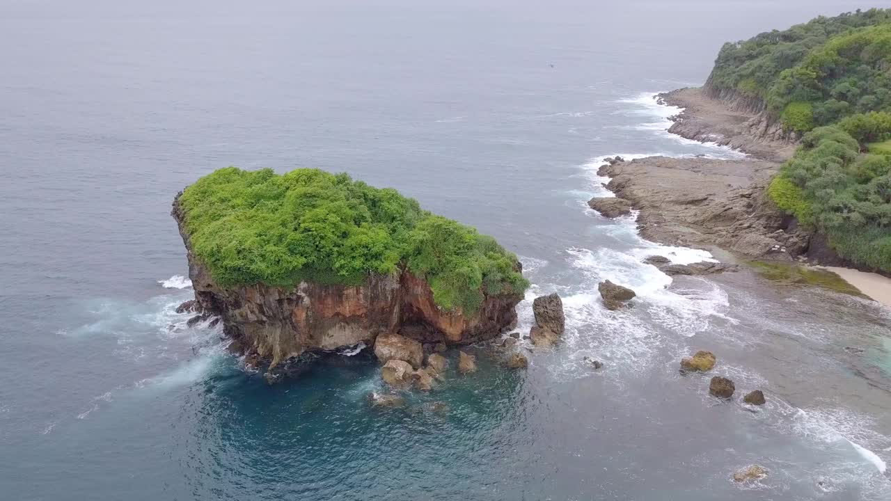 无人机拍摄的珊瑚岛被绿树覆盖，被热带海滩的海浪拍打着。视频素材