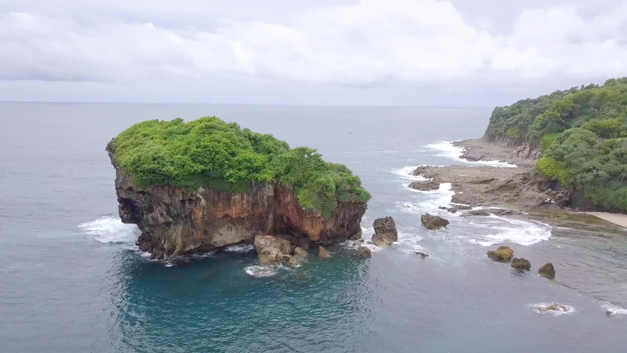 无人机拍摄的珊瑚岛被绿树覆盖，被热带海滩的海浪拍打着。视频素材